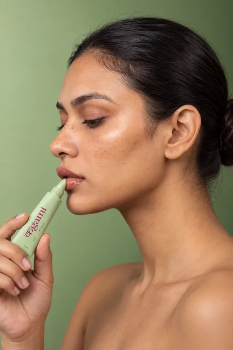 SHAAN applying the DEW green lip balm tube in a beauty portrait