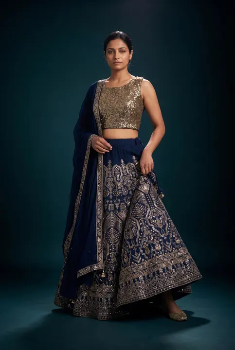 Studio portrait: woman in navy lehenga, gold blouse, teal backdrop