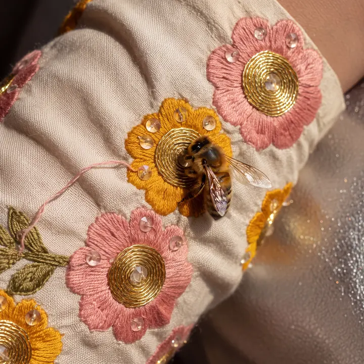 An ivory textile with embroidered bee detail