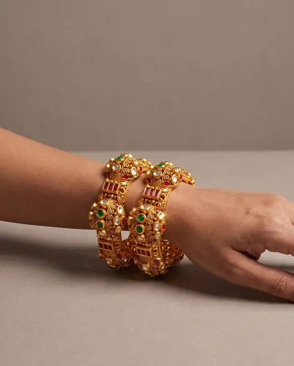 The matching gold ruby and emerald kadas worn on a wrist