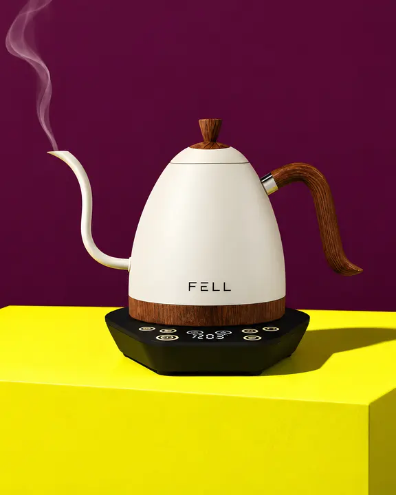 A sculptural white kettle on citron against plum, with a wisp of steam