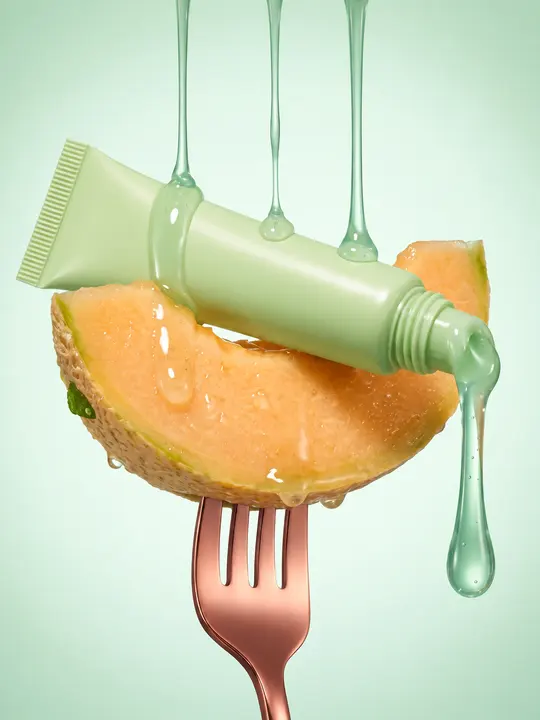 A green beauty tube and melon on a fork, suspended in dripping gel